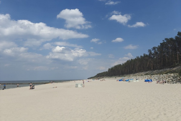 Plaża z niewielką liczbą ludzi pod błękitnym niebem. Pogorzelica